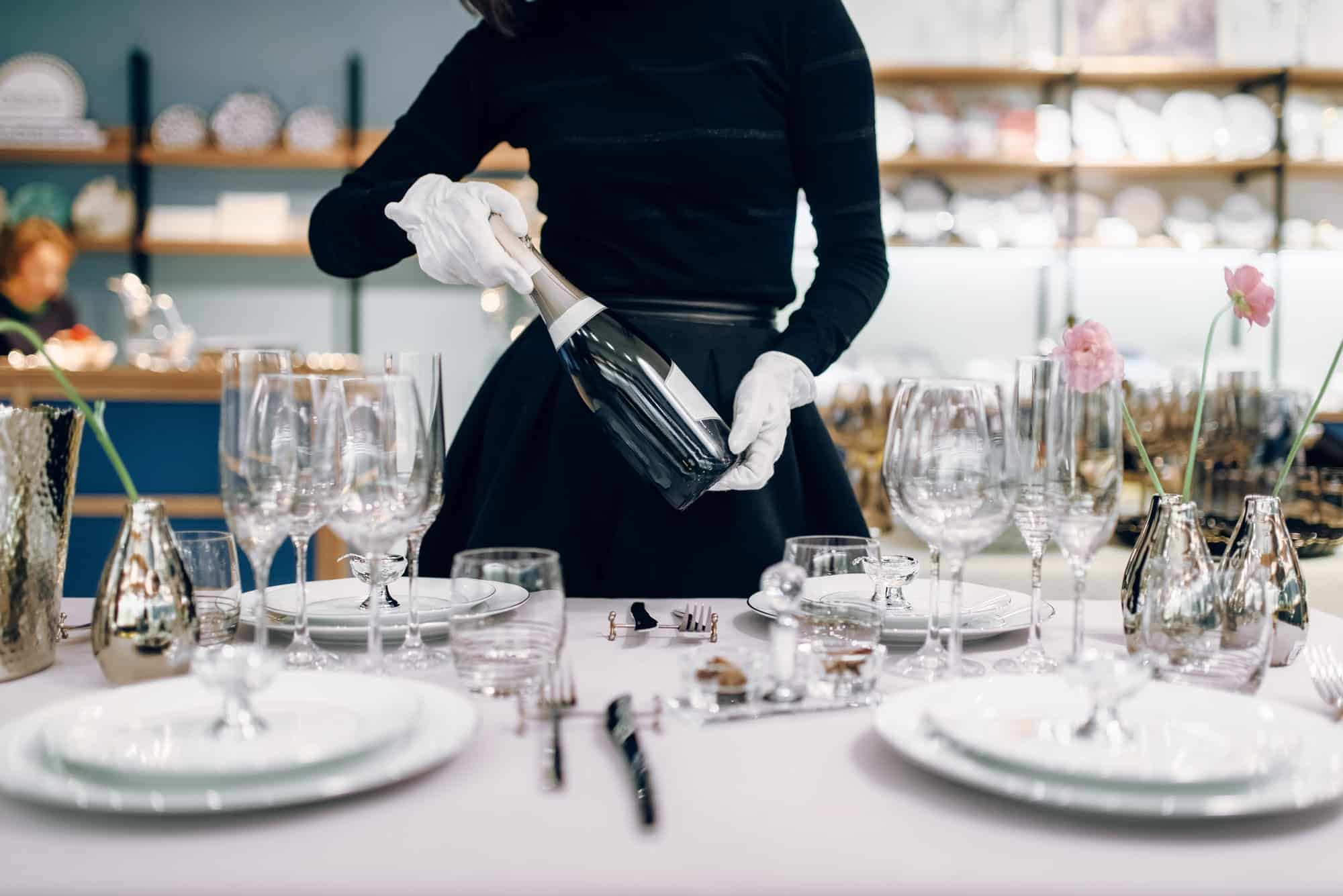 Waitress with a bottle of champagne, table setting