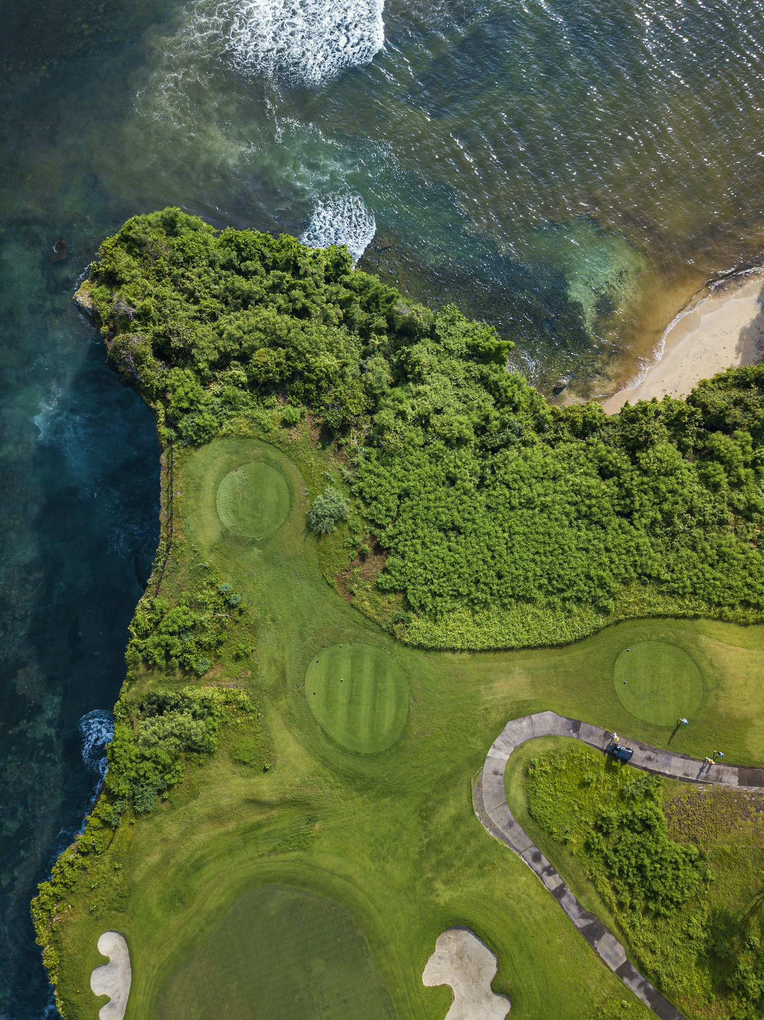 Aerial view of golf course with green at coast